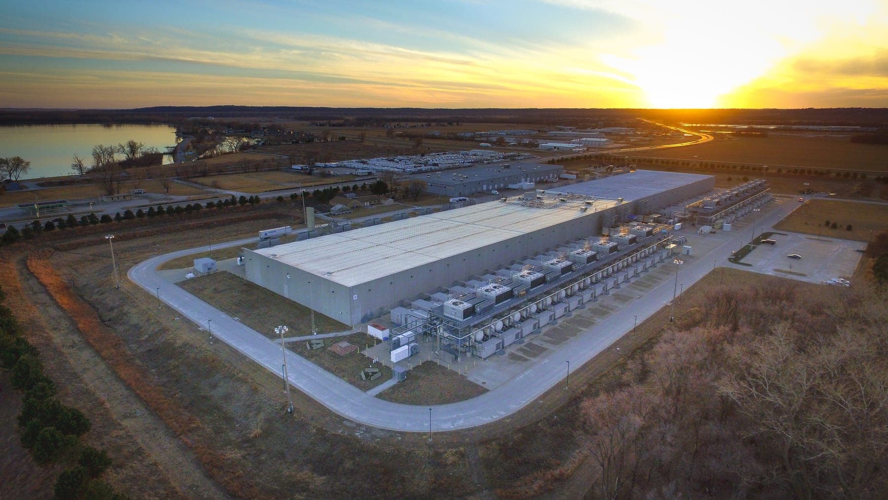 Vista aerea al tramonto del data center di Google a Council Bluffs, in Iowa: un edificio rettangolare enorme circondato da campi, con le unità di raffreddamento allineate sul lato lungo.